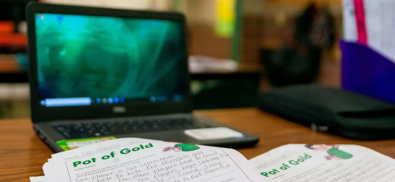 Wingate Elementary School Blurred Laptop on Student Desk with Student's Pot of Gold Assignment In Focus on Desk.